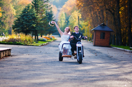 Happy wedding couple on three wheel bikeの写真素材