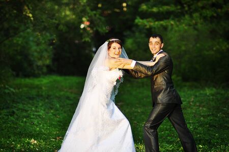 Playful wedding couple on green woodの写真素材