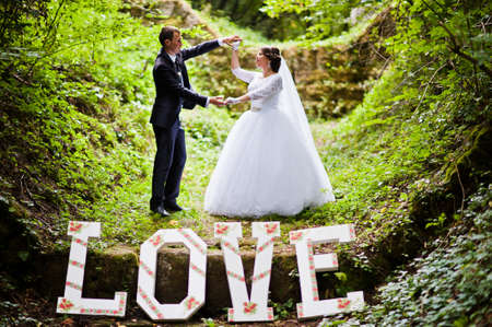 Wedding couple at green alley with big word loveの写真素材
