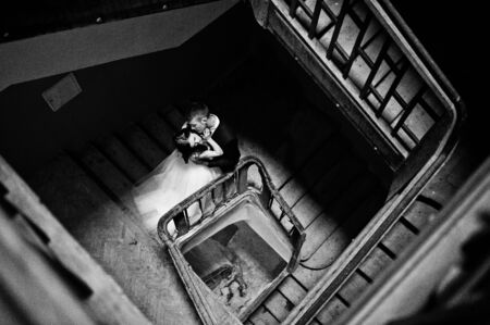 Wedding couple at wooden stairs in the entrance of an old house