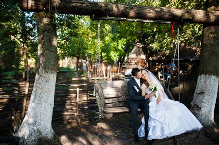 Wedding couple sitting on the large wooden swingの写真素材