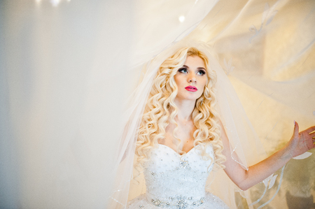 Curly blonde bride  posing on curtainsの写真素材