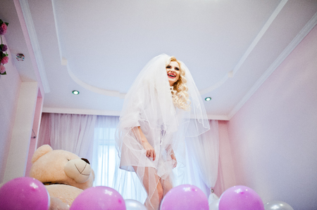 Young sexy blonde bride having fun at her pink roomの写真素材