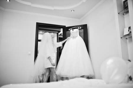 Young beautiful blonde bride looking at her wedding dressの写真素材