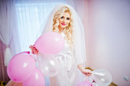 Young sexy blonde bride having fun at her pink roomの写真素材