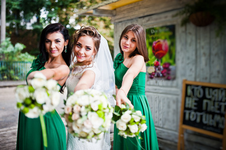 Thre charming bride and bridesmaids showing wedding bouquets at they handsの写真素材