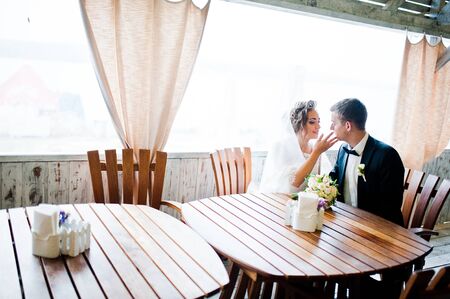 Wedding couple sitting at a table in a cafeの写真素材