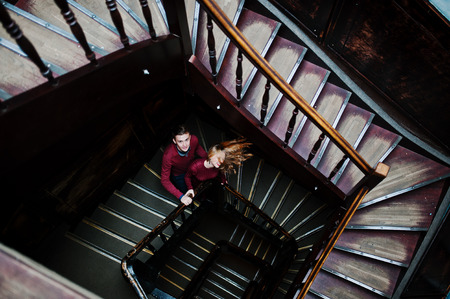 Young beautiful stylish couple in a red dress in big wooden vintage stairsの写真素材