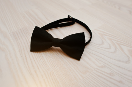 Black cotton bow tie on light wooden backgroundの写真素材