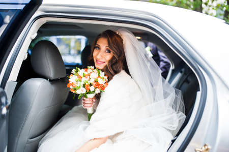 Cute curly bride looking from elegant wedding carの写真素材
