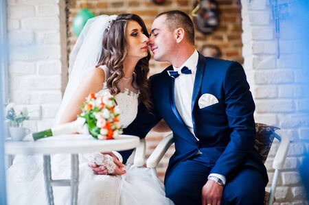 Wedding couple sitting at a table in a cafeの写真素材
