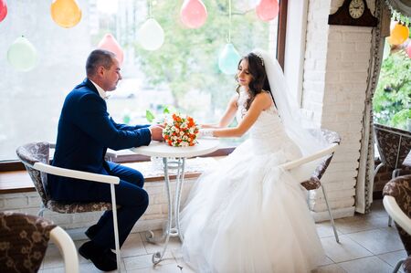 Wedding couple sitting at a table in a cafeの写真素材