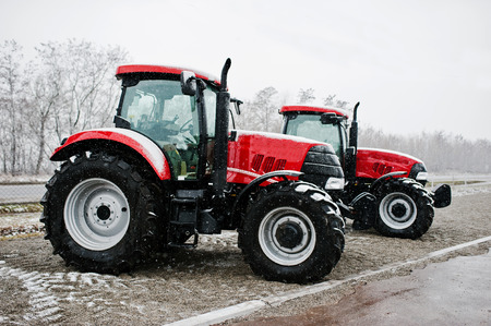 Two new red tractor stay at snowy weatherの写真素材