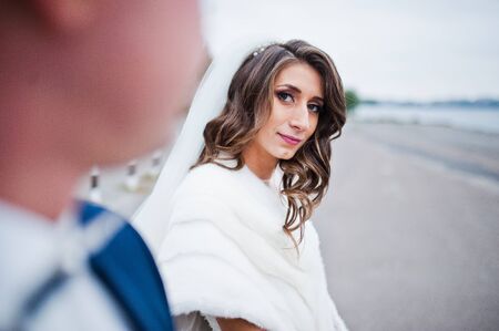 Close up wedding portrait of couple in cloudy weather on the background of the pier at the lakeの写真素材