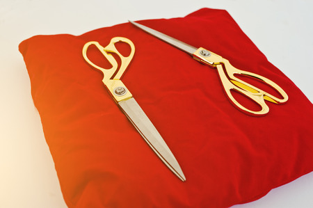 Gold scissors on a red silk cushion for grand opening
