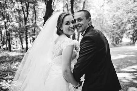 Fashionable wedding couple looking back smiling. B&W photoの写真素材