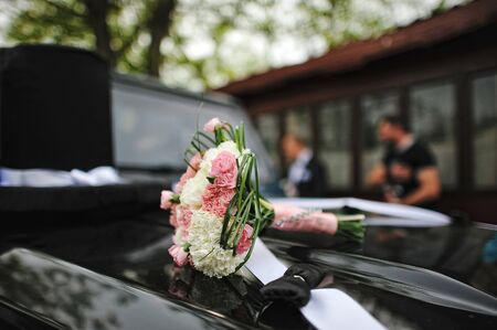 Wedding bouquet on the hood of car with big decor hatの写真素材