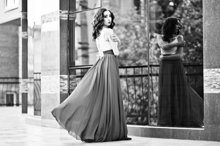 Portrait of fashionable girl at red evening dress posed background mirror window of modern building. Black and white photoの写真素材