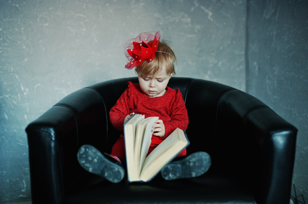 Little cute princess girl sitting on a chair and read old bookの写真素材