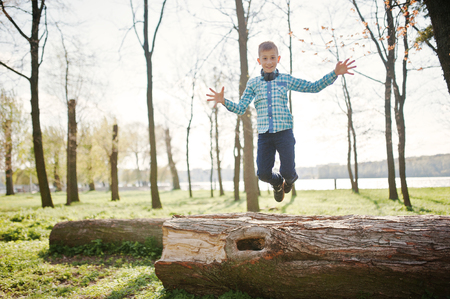 Little fun boy jump froom tree stump at parkの写真素材