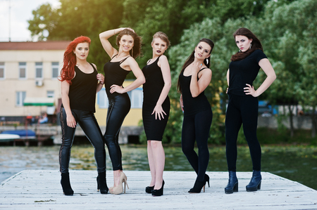 Five beautiful young sexy girls models in black tight dress posing on pierの写真素材