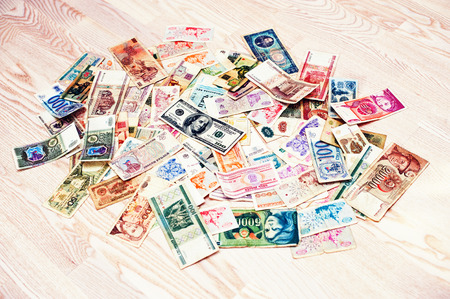 Many old money of different countries with 100 dollar bill on wooden backgroundの写真素材
