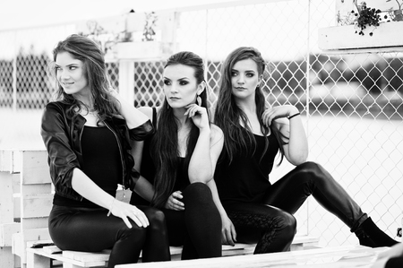 Portrait of three fashion girls sitting on bench at pierの写真素材