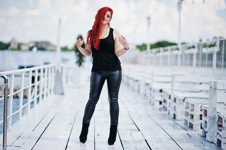 Young red haired girl at black clothes posed on the pierの写真素材