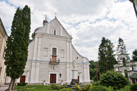 White stone catholic church with a bell tower and monument of Holy Maryの写真素材