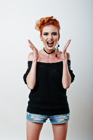 Studio portrait of red haired girl on black blouse and jeans shorts with bright dark make upの写真素材