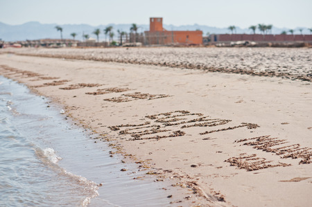 Inscriptions on the sand with sea wavesの写真素材