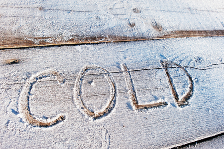 Cold written on a wooden background with frostsの写真素材