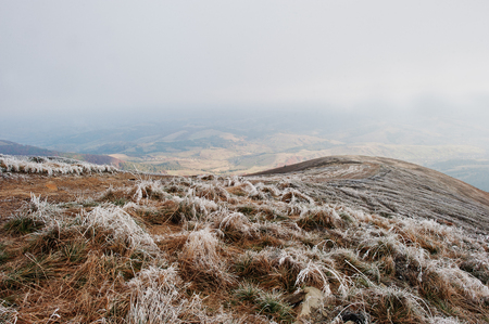 Mountainsides with frozen grass and fog on hill.の写真素材
