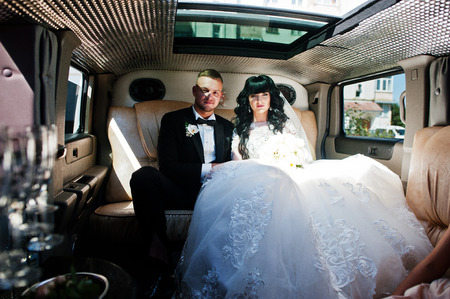 Amazing wedding couple inside elegance limousine at their awesome wedding day.の写真素材