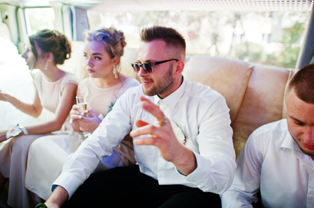 Stylish groomsman or best man of groom and bridesmaids inside limousine at wedding party.