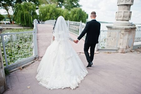 Back view of walking wedding couple at bridge to island of love.の写真素材