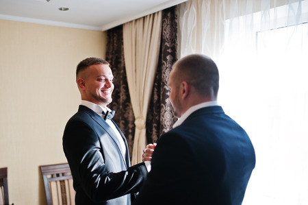 Two handsome male friends meet and shaking hands each other. Groomsman or best man greeting groom at wedding day.の写真素材
