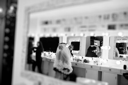 Make up artist doing professional makeup of young woman bride near the mirror in beauty studio on...