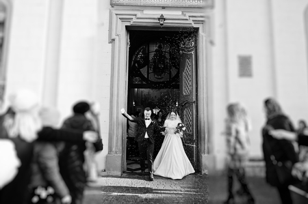 Guests showered newlyweds with colorful  rice after wedding ceremony at church. Black and white...