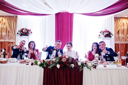 Wedding couple with best mans and bridesmaids sitting on table at restaurant.の写真素材