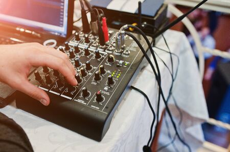 Hand of man on digital mixing console. Sound mixer control panel, closeup of audio faders.