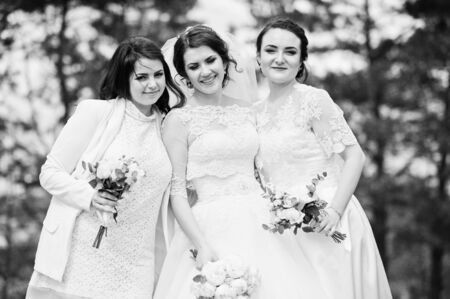 Pretty bride with bridesmaids on white dresses with bouquets on hands at wedding day. Black and white photoの写真素材