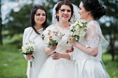 Pretty bride with bridesmaids on white dresses with bouquets on hands at wedding day.の写真素材