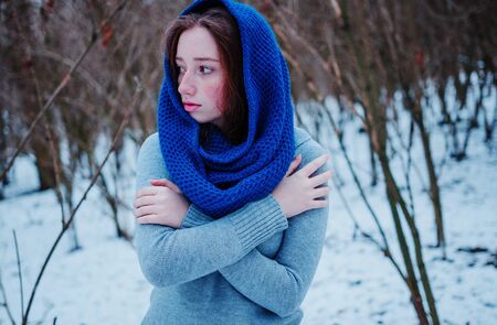 Portrait of young red hair girl with freckles wearing at blue knitted wool scarf in winter day.の写真素材