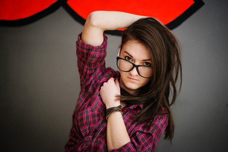 Portrait of brunette girl on glasses wearing casual clothes background gray wall with some graffity.の写真素材