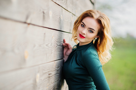 Yong elegance blonde girl at green dress background wooden texture.の写真素材