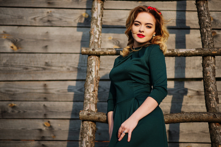 Yong elegance blonde girl at green dress background wooden staircase.の写真素材