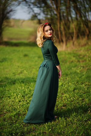 Yong elegance blonde girl at green dress on the garden in spring.の写真素材