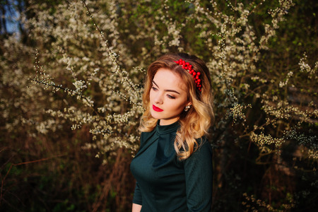 Close up portrait of yong elegance blonde girl at green dress on the garden in spring on blossom trees.の写真素材