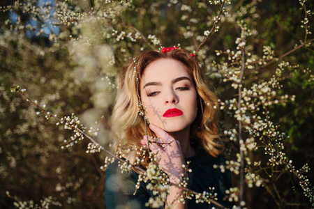 Close up portrait of yong elegance blonde girl at green dress on the garden in spring on blossom trees.の写真素材